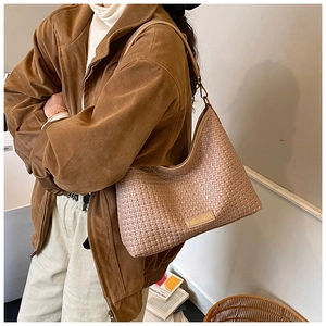 Close-up of beige woven texture and gold metal logo on a stylish Hobo shoulder bag