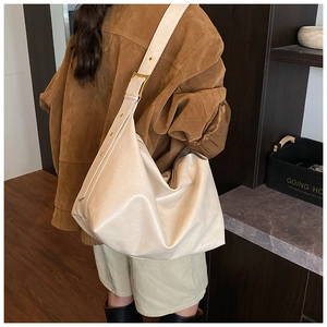 Side view of cream large hobo bag with adjustable wide strap on model for commuting