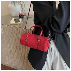 Detail of red cylindrical Boston bag in suede finish with metal buckle leather straps