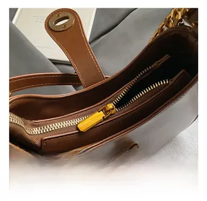Détail du sac en cuir marron brillant avec fermoir rotatif doré et chaîne métallique épaisse