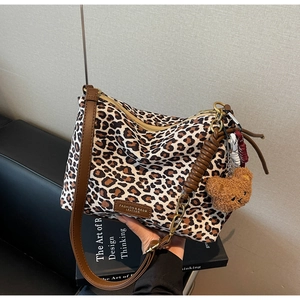 Close-up of leopard print tote bag with woven brown handle and plush bear charm