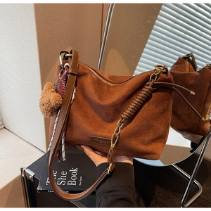 Détail d'un cabas en daim marron avec chaîne vintage, breloque ours et foulard en soie