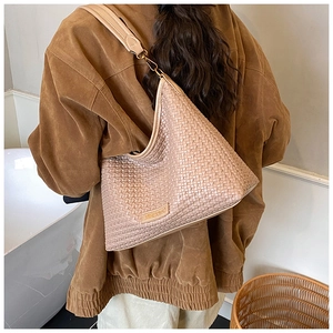 Close-up of beige woven texture and brand logo tag on minimalist crossbody shoulder bag