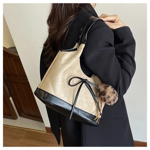 Detail of beige quilted shoulder bag with black trim and leopard faux fur pompom charm