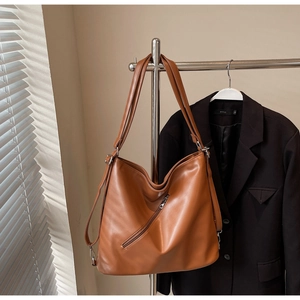 Close-up of brown faux leather tote bag with a diagonal zipper pocket and wide straps