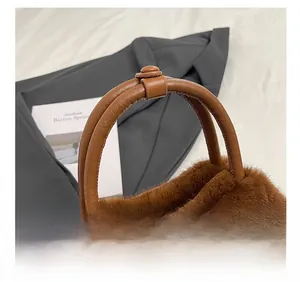 Detail of dark brown plush handbag featuring light brown leather handle with buckle accents