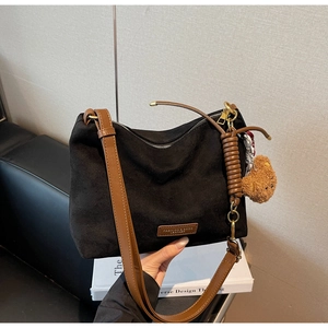 Détail du sac cabas noir mat avec bordure en cuir marron et breloque ours mignon