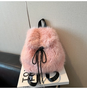 Detail view of pink fluffy backpack with black woven straps and drawstring closure