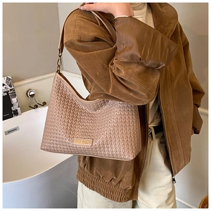 Close-up of beige woven texture underarm bag with gold metal logo and sleek zipper