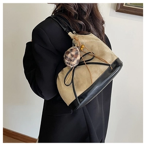 Detail of two-tone tote with beige quilting, black base and decorative leopard charm