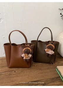 Detail of retro leather bucket bags in caramel and green with cute plush bear charms