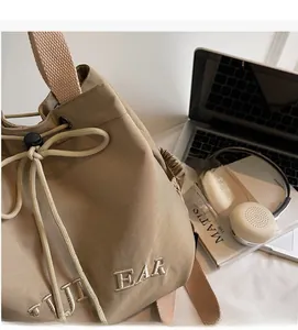 Detail of khaki drawstring bucket bag with JI BEAR embroidery and woven strap