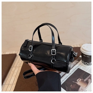 Detail of glossy black barrel bag with silver buckles and elegant dual handles