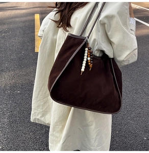 Detail view of deep brown matte suede tote bag with tricolor beaded tassel on a shoulder strap