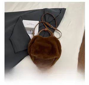 Detail of brown faux fur crossbody bag with round leather handles and adjustable strap