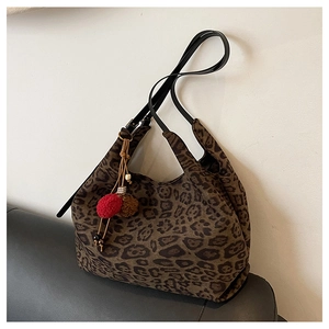 Close-up of leopard print tote bag fabric with red and brown fuzzy pompom charms