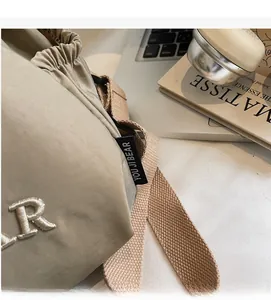 Detail of khaki nylon bucket bag showing YOU JI BEAR label and texture on desk