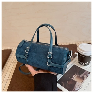 Detail of navy blue cylindrical crossbody bag featuring matte leather and silver buckles