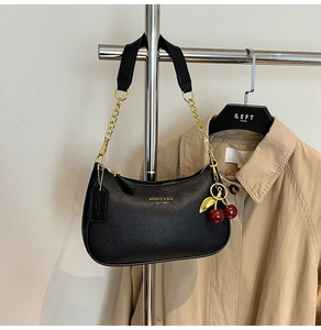 Detail view of black pebble leather hobo bag with gold chain strap and cherry charm detail