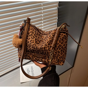 Detail of leopard print tote bag with brown plush bear charm and leather strap