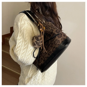 Close-up of leopard print shoulder bag with plush ball and beaded tassels detail