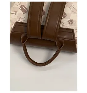 Détail des bretelles en cuir marron renforcé sur un sac à dos à carreaux crème
