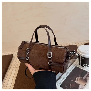 Detail of a dark brown suede cylinder bucket bag with leather trim and silver buckle