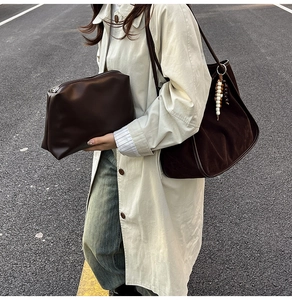 Brown bucket bag and matching pouch styled with an elegant beige trench coat outdoors