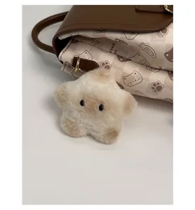 Gros plan d'un joli charm étoile en peluche avec chaîne dorée sur un sac à dos