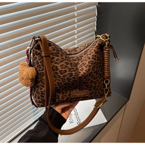 Detail of leopard print hobo bag with gold hardware and plush bear charm accessory