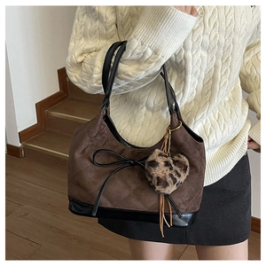 Close-up of brown quilted shoulder bag with black bow and leopard heart charm detail