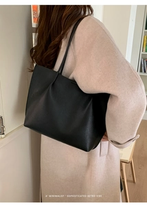 Minimalist black leather tote bag shown on shoulder for an elegant retro commute look