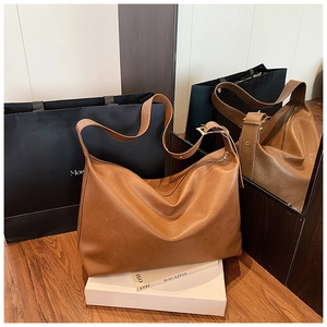 Detailed shot of large brown leather tote bag with natural texture and golden buckles