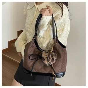 Detail of a brown quilted leather underarm bag with leopard print charm and bow