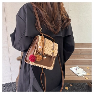 Chic brown leather and beige faux fur shoulder bag with plush pompom on outdoor bench