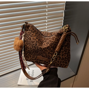 Detail of leopard print tote featuring a plush bear charm and woven rope accessories