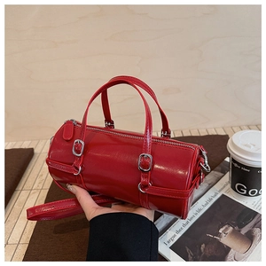 Close-up of red cylinder handbag with silver hardware and adjustable shoulder strap