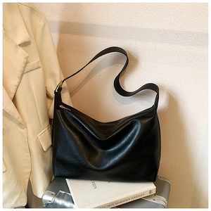 Detail of minimalist black hobo bag on a silver suitcase in a travel and commute setting