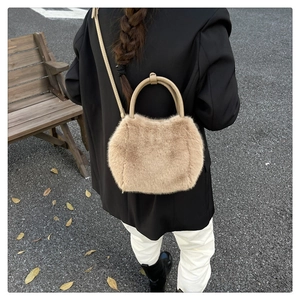 Detail of soft faux fur handbag with leather strap on an outdoor autumn street background