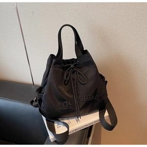 Detail of Youthbear embroidery on black nylon drawstring bucket bag with webbing straps