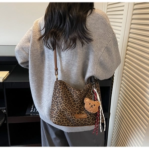 Detail of leopard print tote bag with leather label and brown plush bear charm