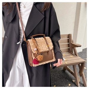 Detail of a brown leather and beige faux fur crossbody bag with cute plush pompom charms