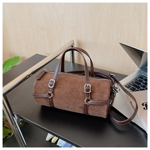 Detail of brown suede cylinder bag with leather trim and silver metal hardware