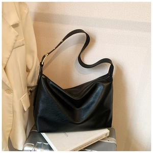 Detail of soft black leather tote bag with adjustable strap on a silver suitcase