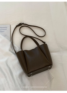 Detail of dark brown lychee leather tote bag with metal feet and adjustable strap