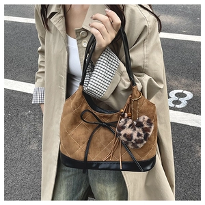 Detail of brown suede bucket bag with quilted patterns and leopard heart charm