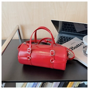Detail of red cylinder handbag in glossy leather with silver buckles and a shoulder strap