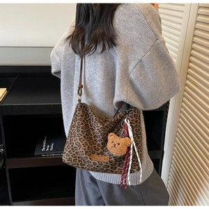 Detail of leopard print tote bag with brown teddy bear charm and leather strap