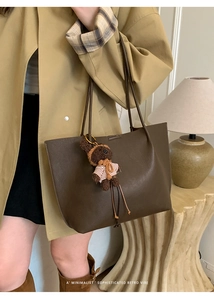 Close-up of brown pebbled leather tote bag featuring a cute teddy bear charm pendant