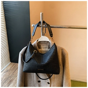 Detail of black woven hobo bag with gold hardware displayed on a stylish wool coat